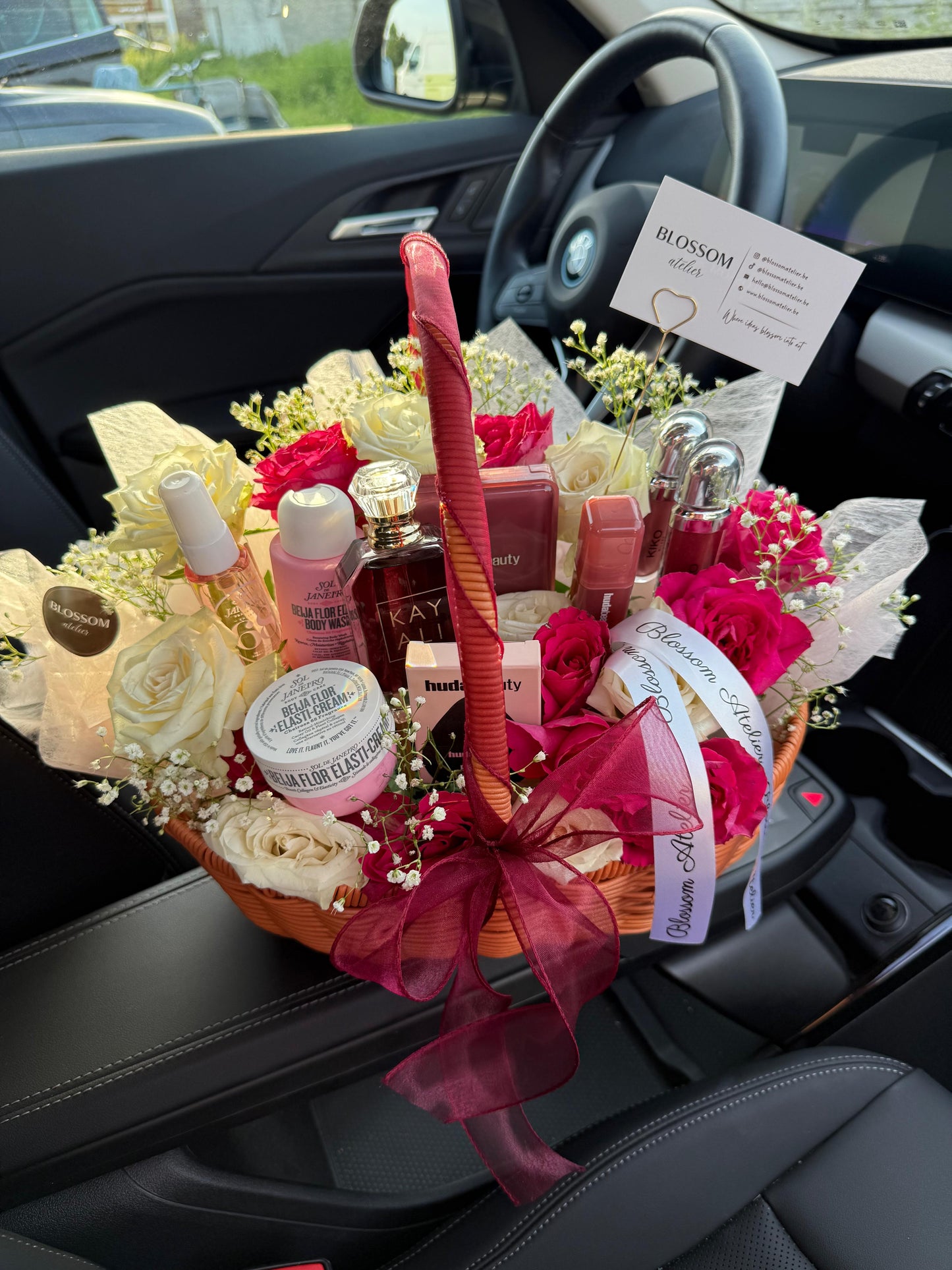 Gift basket with beauty products and flowers inside a car.
