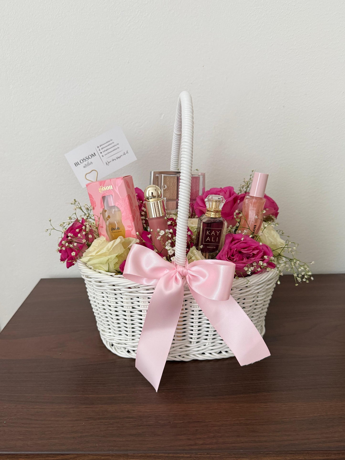 Gift basket with flowers and perfumes on a wooden surface